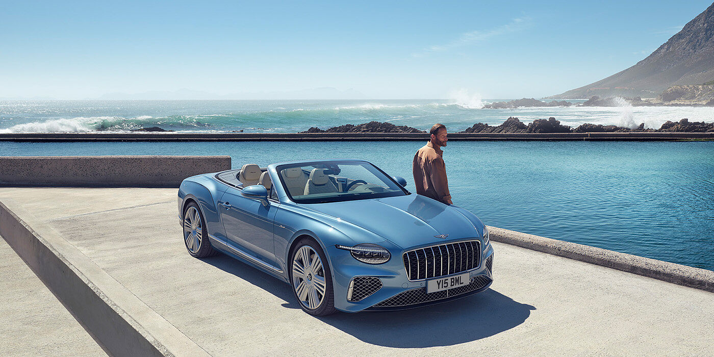 Bentley Singapore New Bentley Continental GTC Azure convertible front view in Light Windsor blue paint with 22 inch ten spoke wheels parked by the sea in the sunshine