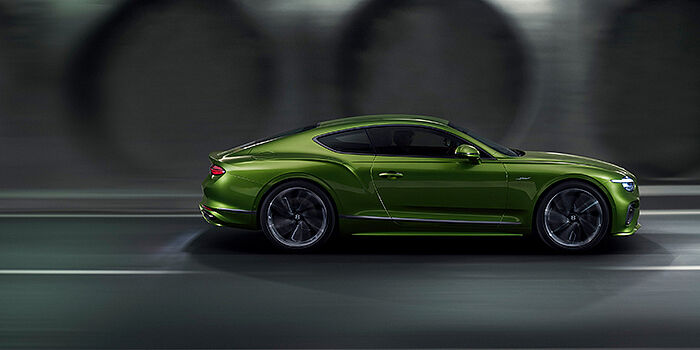  Bentley Singapore Bentley Continental GT coupe in Tourmaline Green paint driving in profile on a dark road