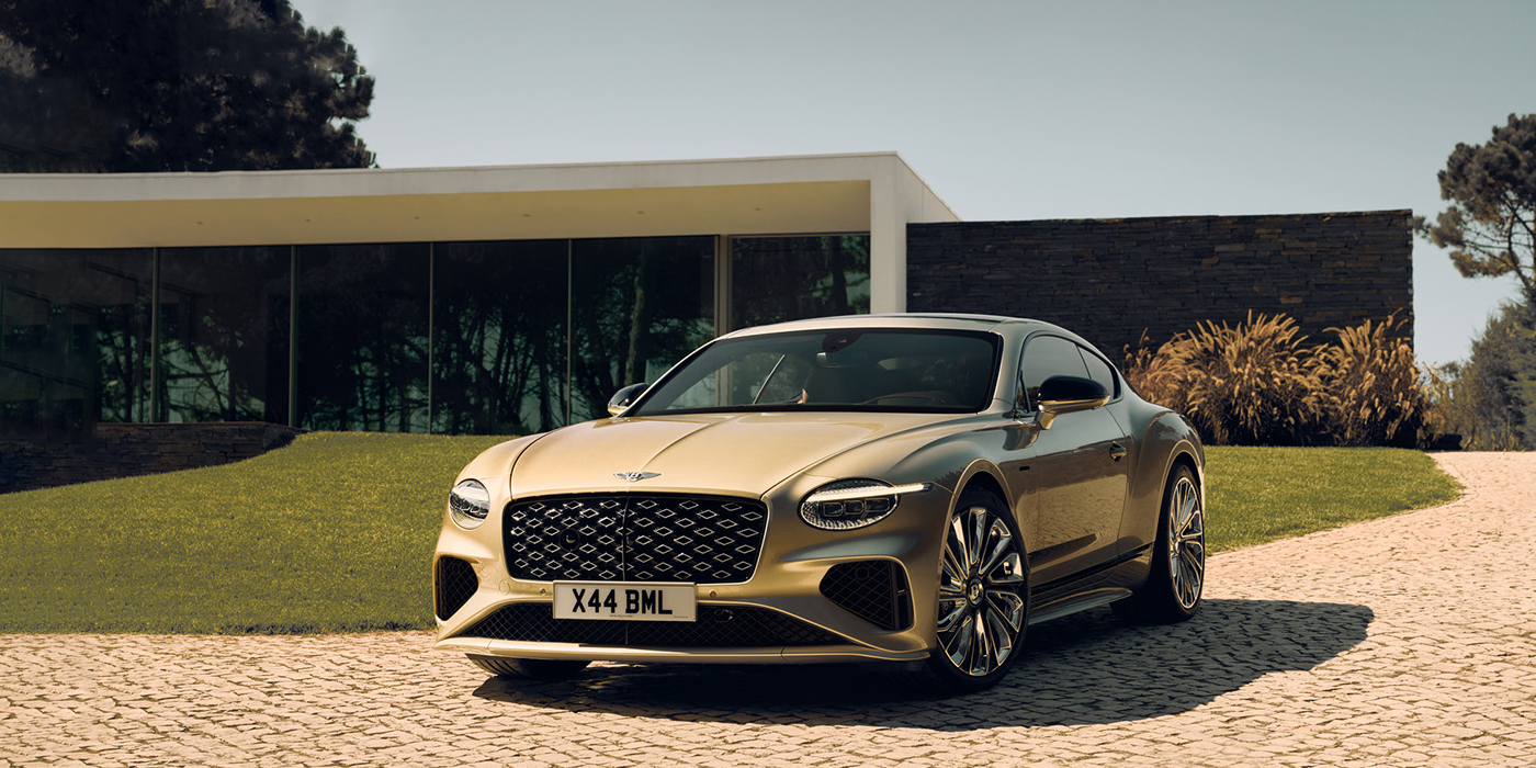 Bentley Singapore Bentley Continental GT Mulliner coupe front three quarters in Patina paint parked outside a glass fronted building with a grass lawn behind it