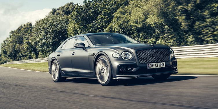 Bentley Singapore Bentley Flying Spur Mulliner sedan front three quarter in dark grey paint driving dynamically by some trees on a track