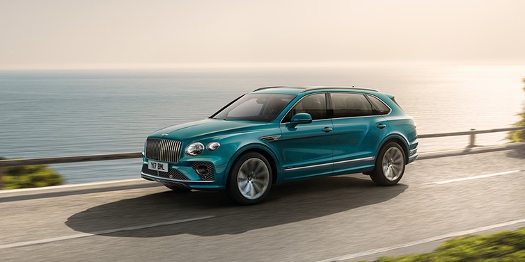 Bentley Singapore Bentley Bentayga Extended Wheelbase Azure SUV in Topaz blue paint driving dynamically by the ocean