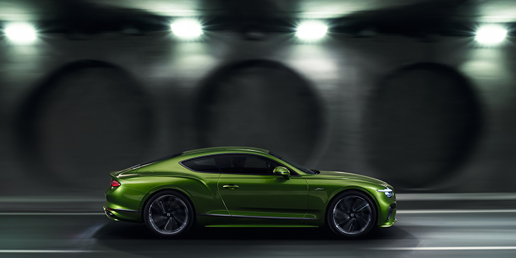 Bentley Singapore Bentley Continental GT Speed coupe profile in Tourmaline Green driving dynamically past a concrete wall at night