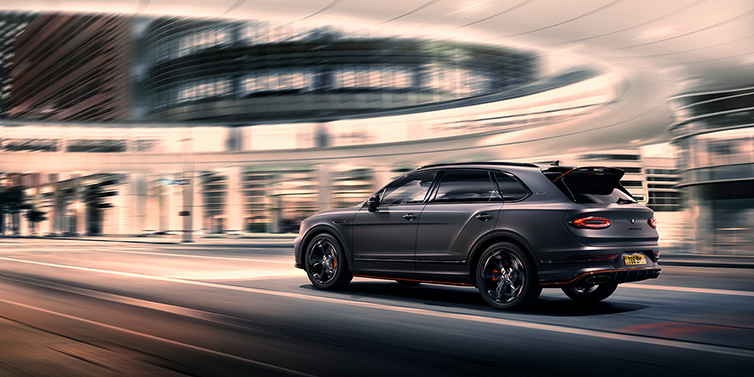 Bentley Singapore Bentley Bentayga S Black Edition SUV rear three quarter in Anthracite Satin paint driving dynamically through a city at night