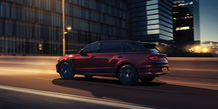 Bentley Singapore Bentley Bentayga Extended Wheelbase Mulliner SUV in Cricket Ball red paint driving dynamically in city at night