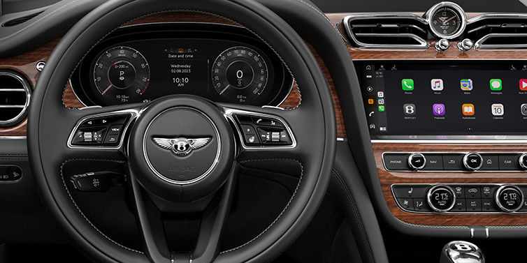 Bentley Singapore Bentley Bentayga SUV front interior detail of steering wheel and driver screens surrounded by Beluga black hide and Crown Cut Walnut veneer