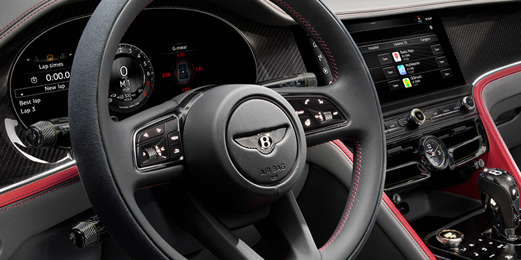 Bentley Singapore Bentley Flying Spur Speed sedan front interior detail showing steering wheel and driver screens surrounded with Hotspur red and Gravity Grey hides